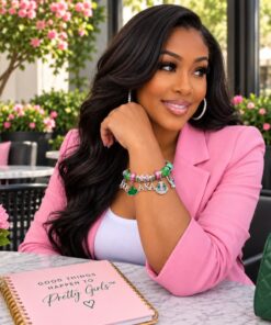 AKA Cherish Charmed Stainless Steel Bracelet on a model sitting at a table with pink blazer with pink flowers in the background